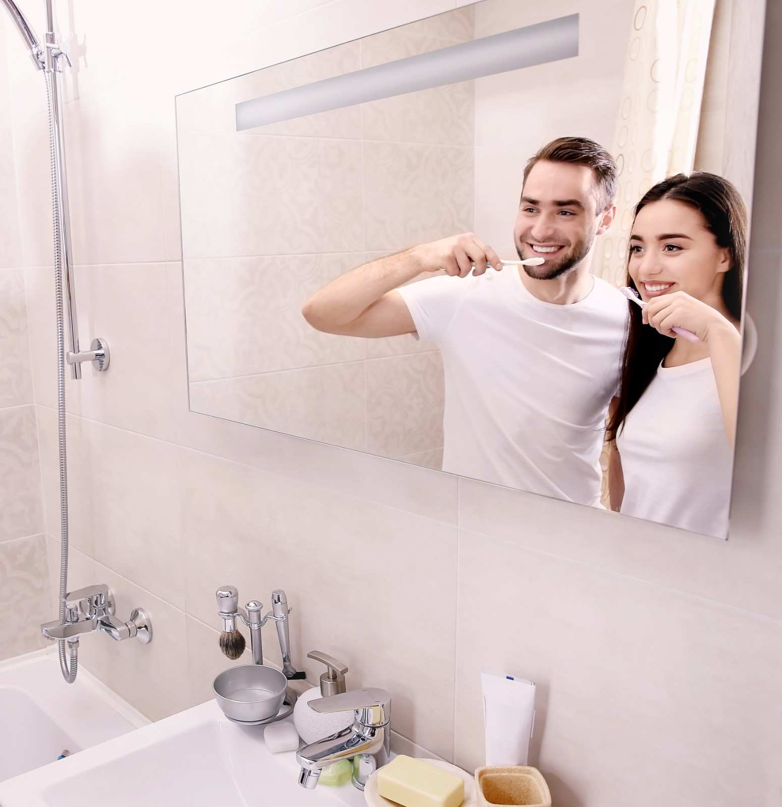 Couple brushing their teeth together in a bathroom mirror.
