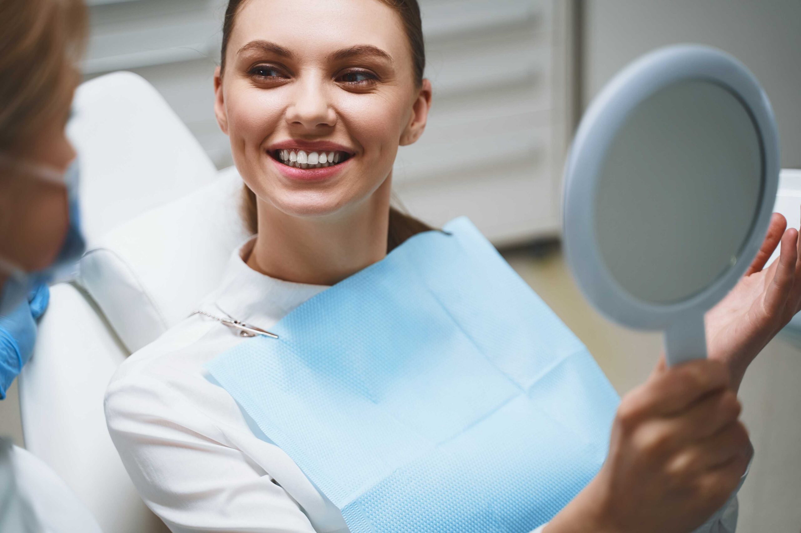 Smiling patient holding a dental mirror.