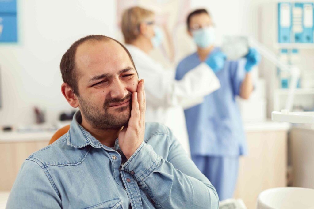 Man experiencing tooth pain at a dental clinic.