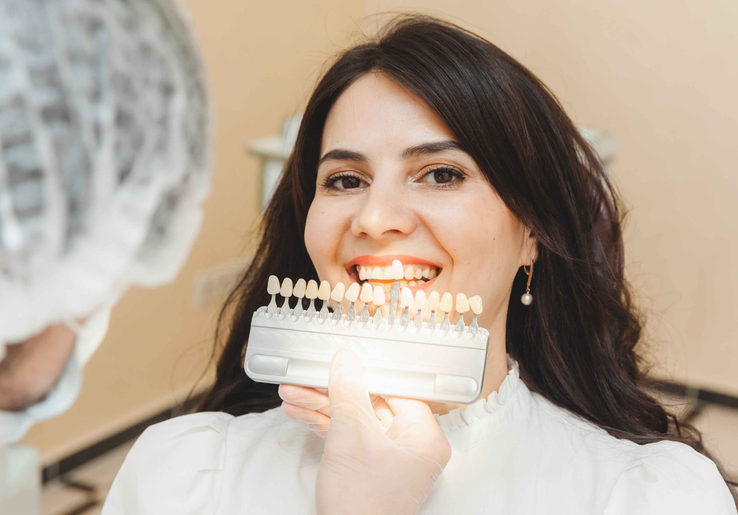 Woman comparing teeth shades with a dental professional.